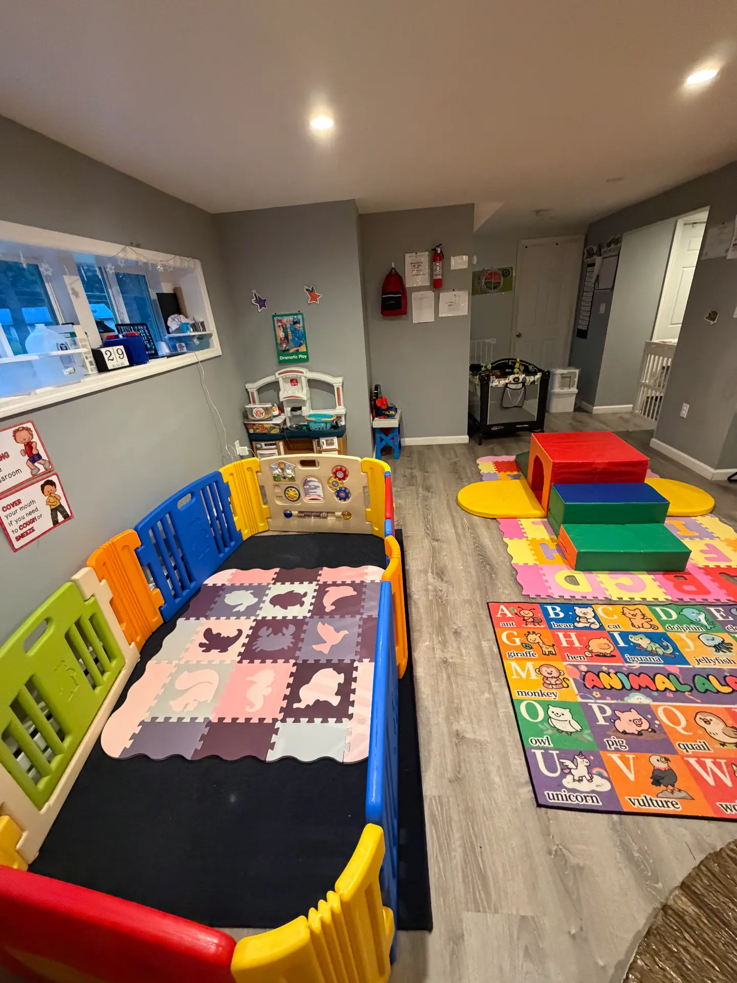Two play areas: a matted enclosure with an activity panel and a soft climbing set on an alphabet mat
