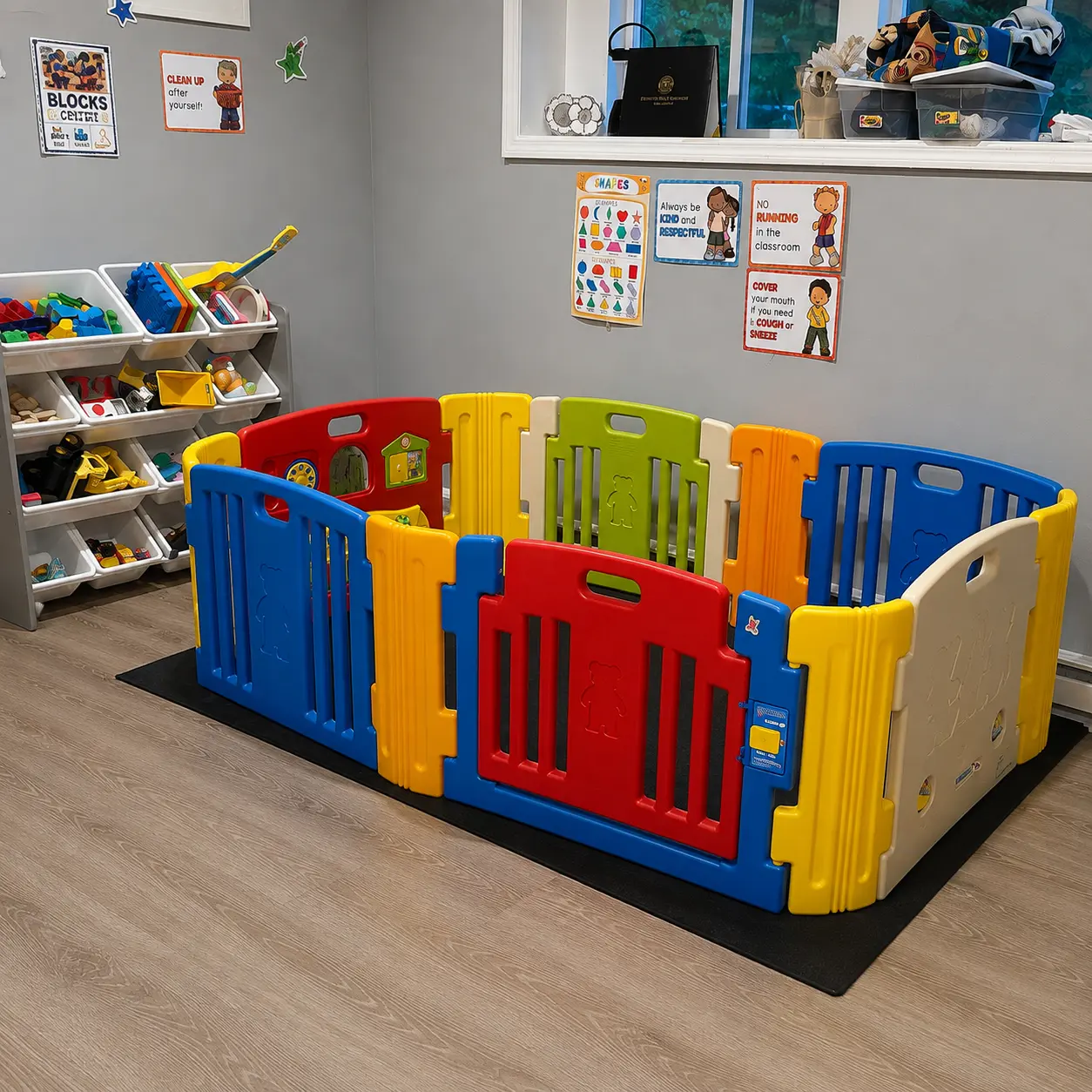 Play yard beside labelled storage bins of blocks and toys, with classroom posters on the wall